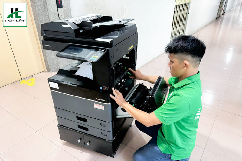 Kỹ thuật viên đang tiến hành kiểm tra và sửa chữa máy Photocopy tận nơi cho khách hàng